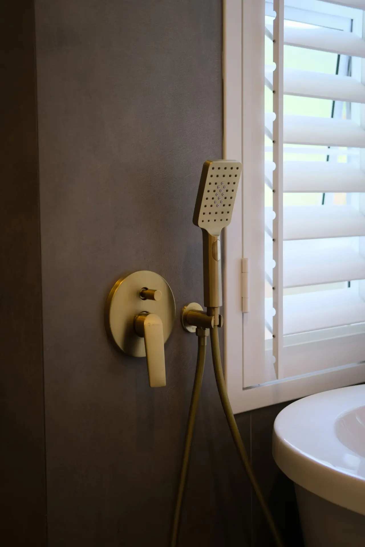 Brushed brass wall-mounted bath mixer and square handheld shower