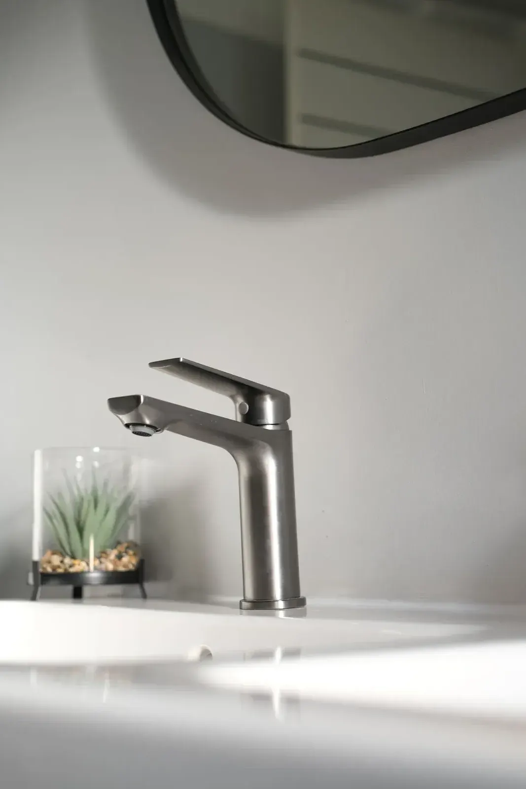 Brushed nickel single-lever basin mixer on a white basin
