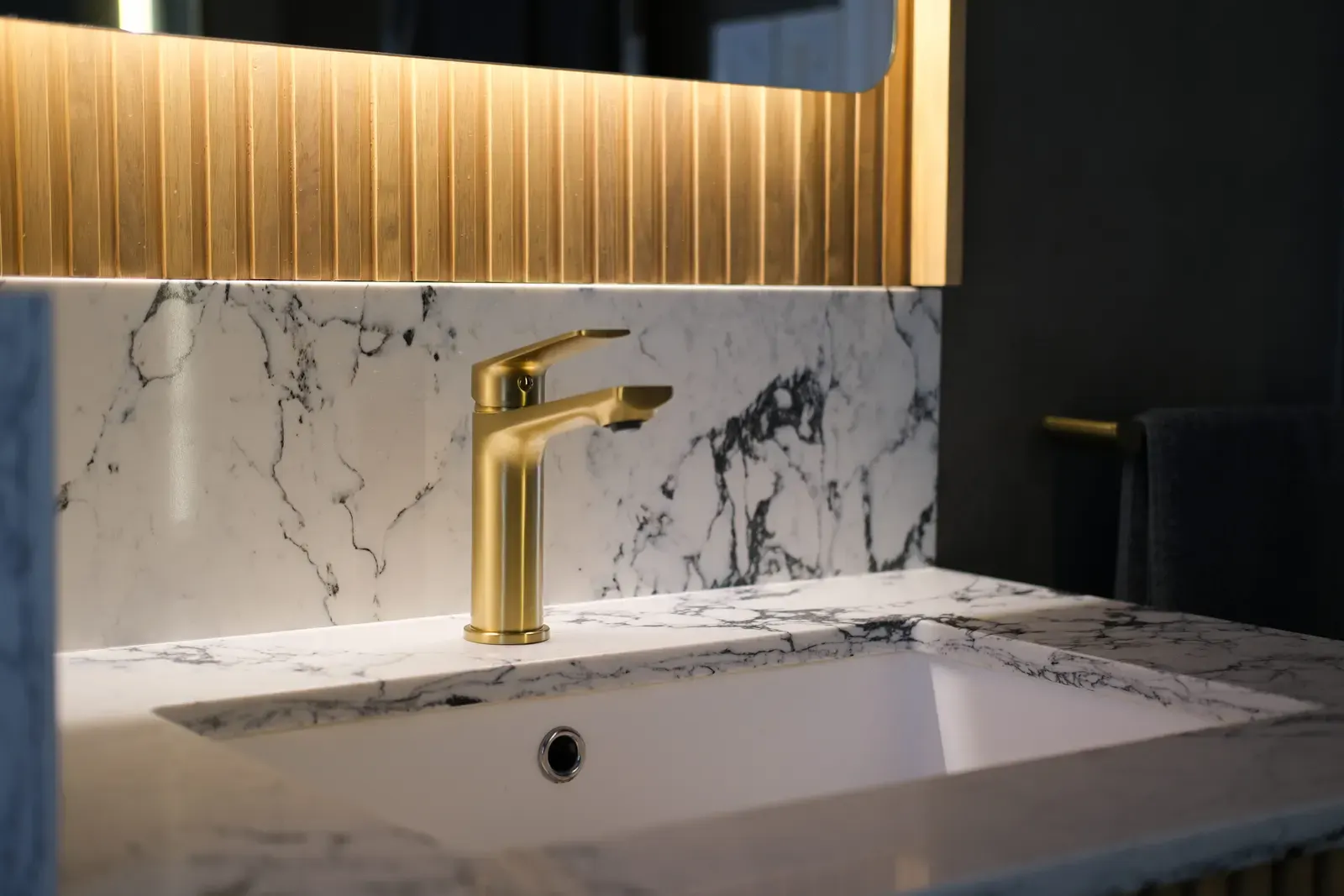 Brushed brass basin mixer on a marble vanity with fluted timber detail