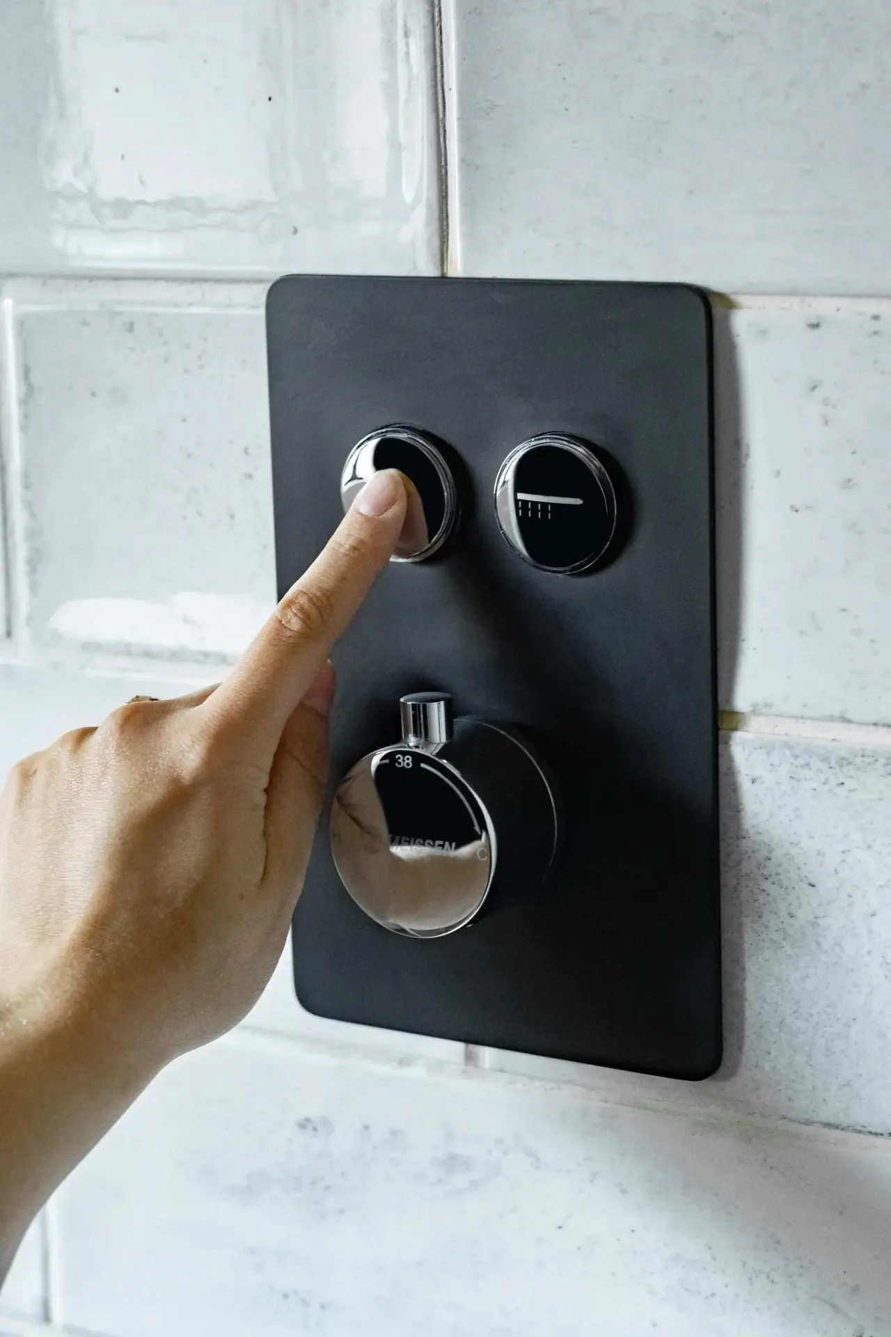 Matte black concealed push-button shower mixer on a tiled wall