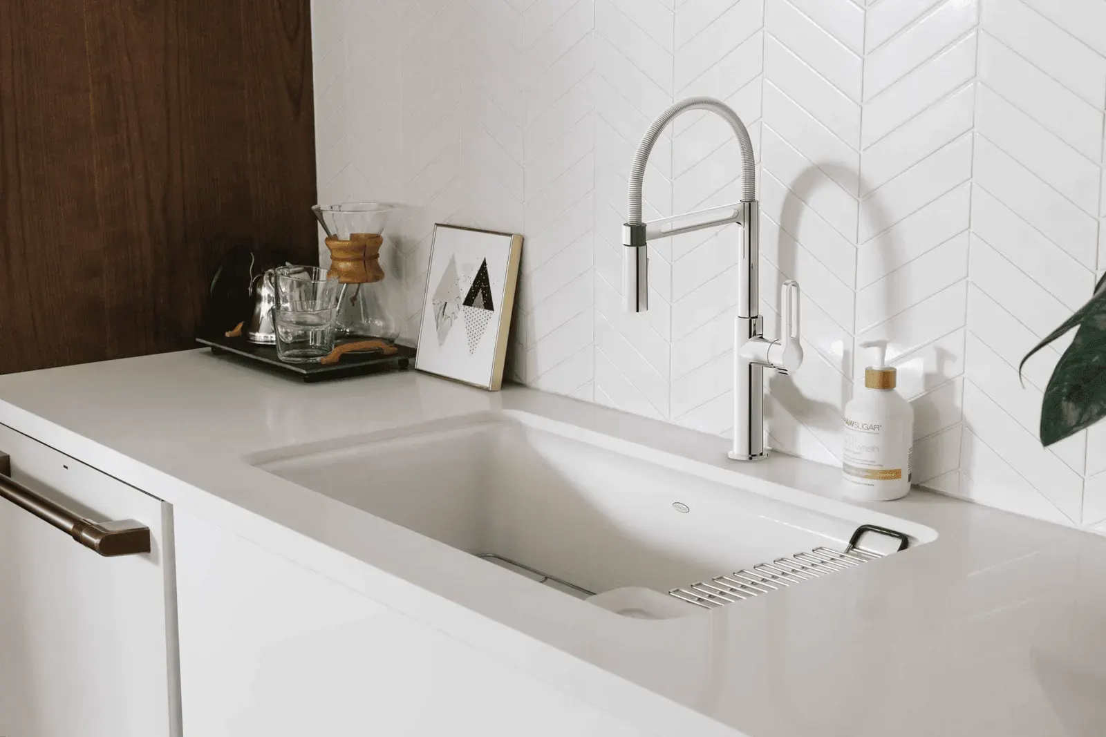 Chrome spring-neck kitchen mixer with pull-out spray over a white undermount sink