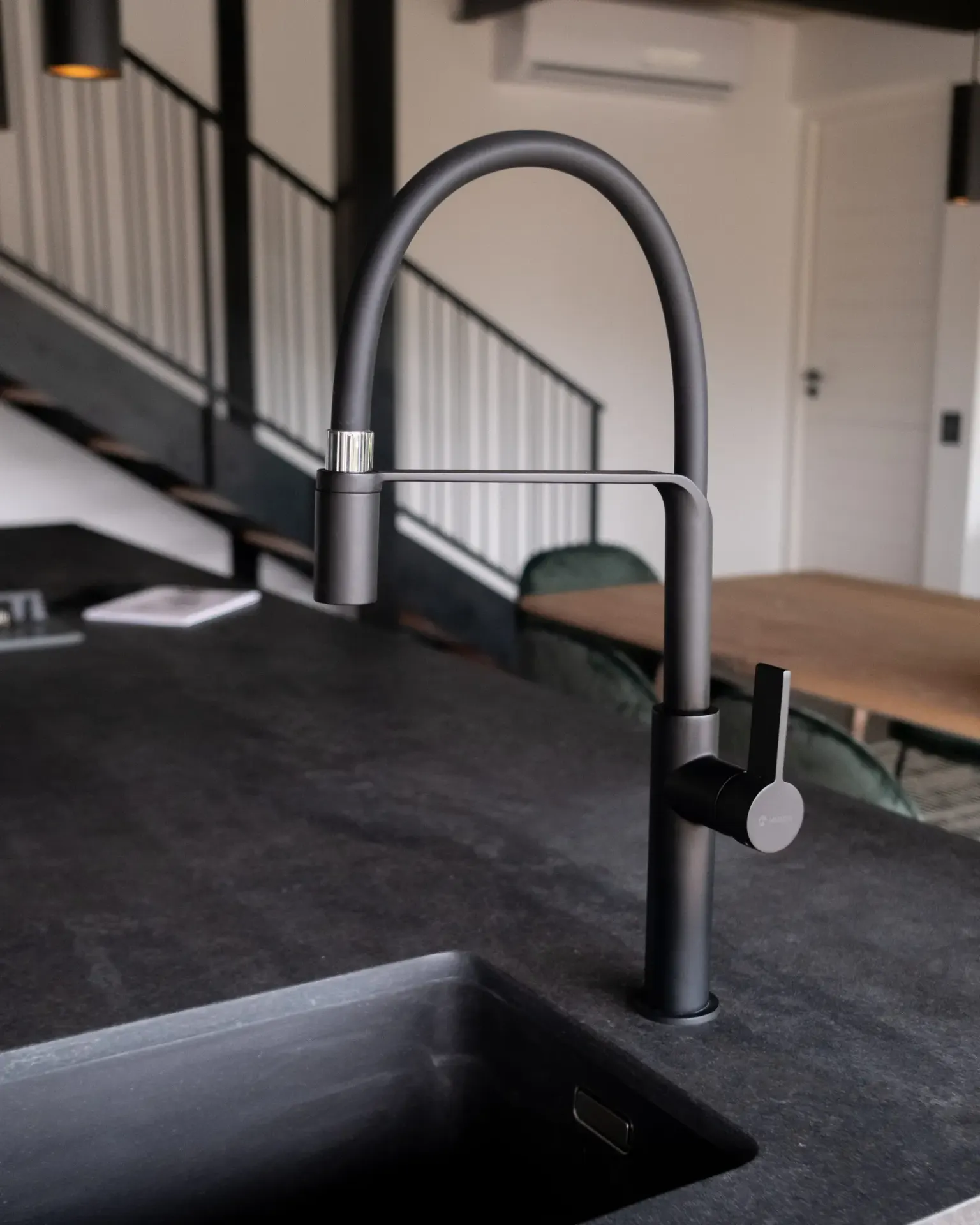 Matte black gooseneck kitchen mixer over a black undermount sink