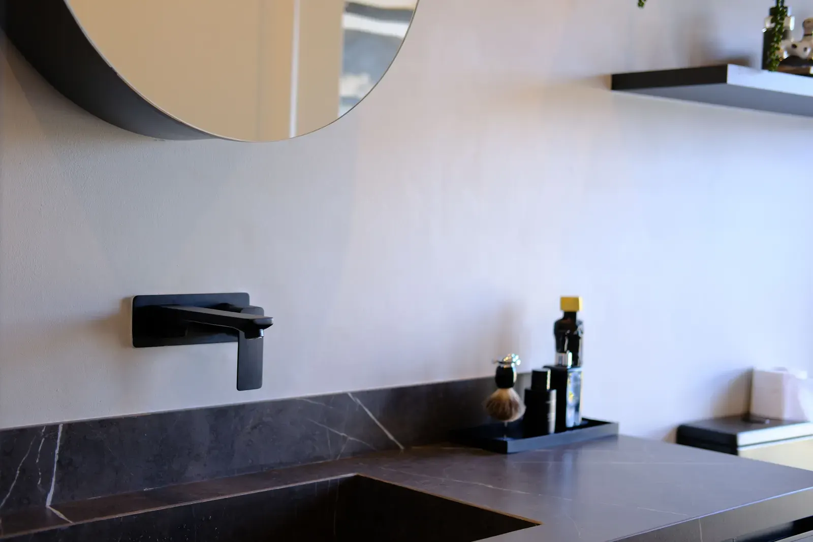 Matte black wall-mounted basin mixer on a dark stone benchtop